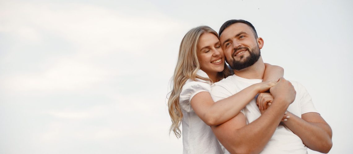 Cute couple in a field. Lady in a white blouse. Guy in a white shirt